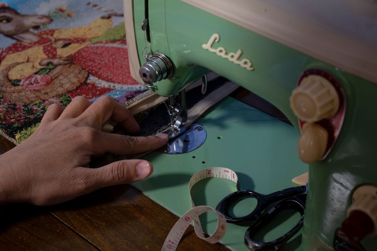 person sewing with sewing machine, scissors, and measuring tape